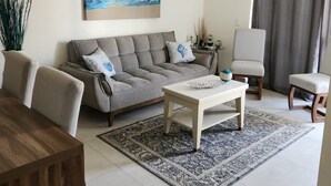 Un soggiorno con divano, tavolino, poltrone, un quadro appeso al muro e una ventola a soffitto.