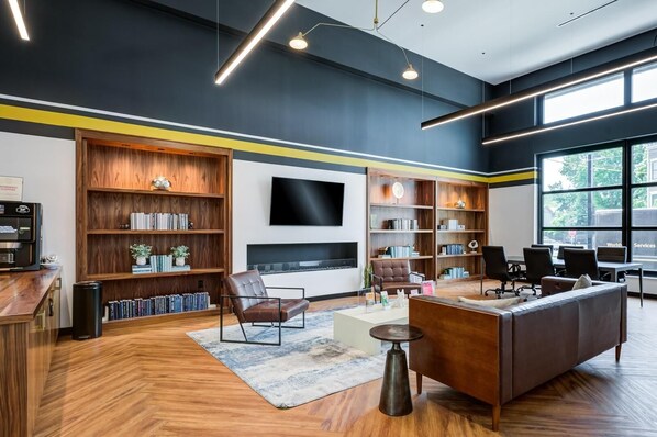 A modern living room with a fireplace, bookshelves, a sofa, and a coffee machine.