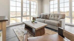 Ein modernes Wohnzimmer mit einer Couch, einem Couchtisch und Blick durch große Fenster.
