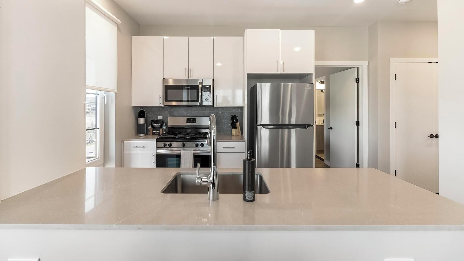 A modern kitchen with stainless steel appliances, a central island, and white cabinetry.