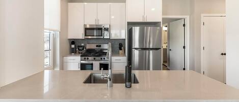 A modern kitchen with stainless steel appliances, a central island, and white cabinetry.