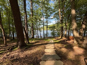 Un sentier de pierres qui traverse une forêt et mène à un lac.