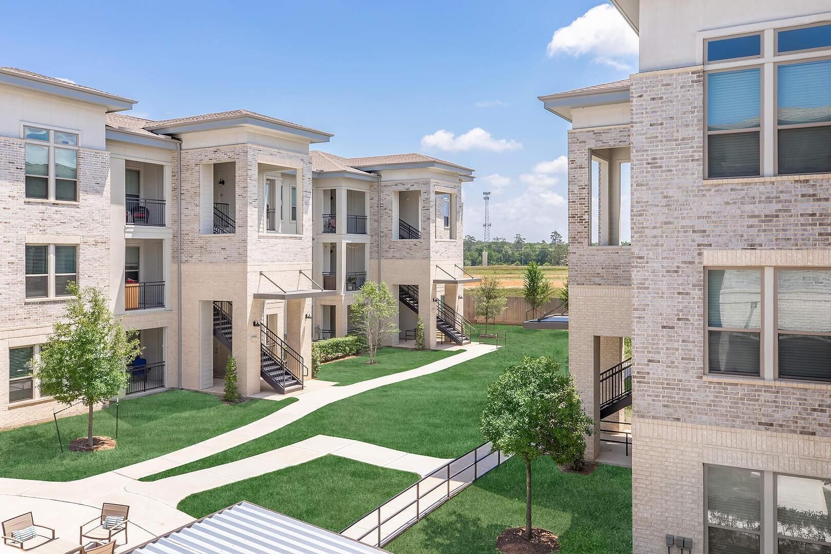 A multi-story residential building with a courtyard, balconies, and a clear sky.