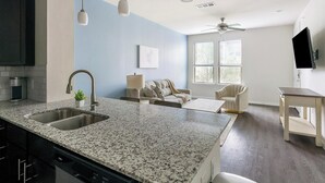 A kitchen with granite countertops, a double sink, and a ceiling fan. - Landing | Stylish 1BD, Gym (Conroe)