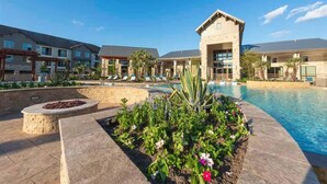 A hotel with a swimming pool, outdoor seating, and a landscaped garden. - Landing | Beautiful 1BD, Gym (New Caney)
