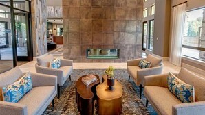 A modern lobby with a large stone wall, two sofas, a coffee table, and a fireplace. - Landing | Beautiful 1BD, Gym (New Caney)