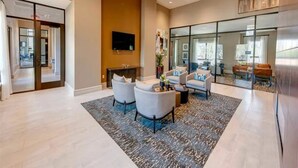 A spacious living area with a fireplace, comfortable seating, and a large window. - Landing | Beautiful 1BD, Gym (New Caney)