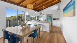 Eine moderne Küche mit weißen Schränken, Holzboden und einem Essbereich mit einem Holztisch und blauen Stühlen.