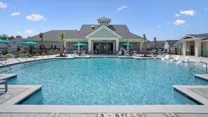 A swimming pool with lounge chairs and umbrellas, surrounded by buildings with a covered entrance. - Landing | Incredible 2BD, Gym (Longs)