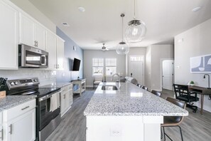 A modern kitchen with granite countertops, stainless steel appliances, and a central island. - Landing | Stylish 2BD, Gym (Longs)