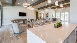 A spacious living area with a large marble island, multiple seating options, and pendant lighting. - Landing | Beautiful 2BD, Gym (Longs)