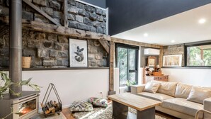 Una sala de estar moderna con pared de piedra, chimenea, sofá y mesa de centro.