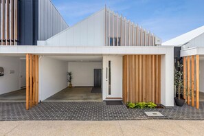 A modern building with a flat roof, a covered entrance area, and a brick-paved driveway.
