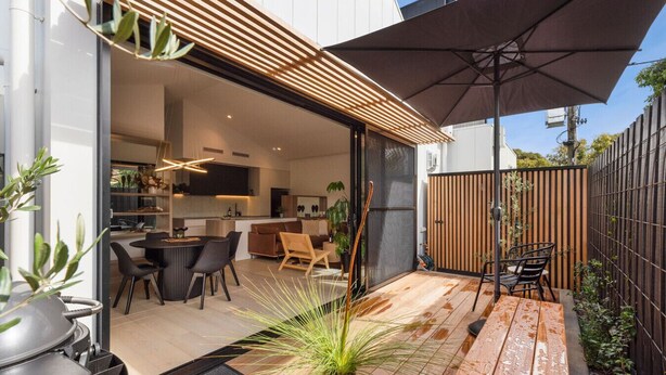 Un espace patio moderne comprenant une table à manger, des chaises et un grand parasol.