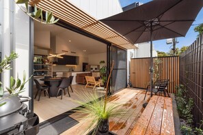 A modern patio area with a dining table, chairs, and a large umbrella.