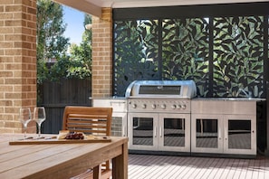 Eine Außenküche mit Grill, einem Tisch und einem Stuhl sowie einer Holzterrasse.