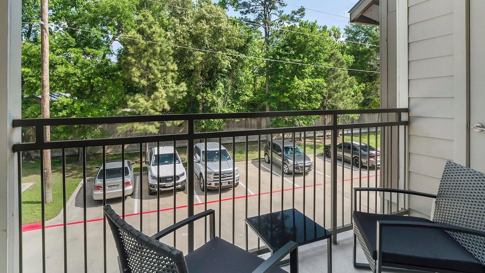Parveke, josta avautuu näkymä parkkipaikalle ja puille.