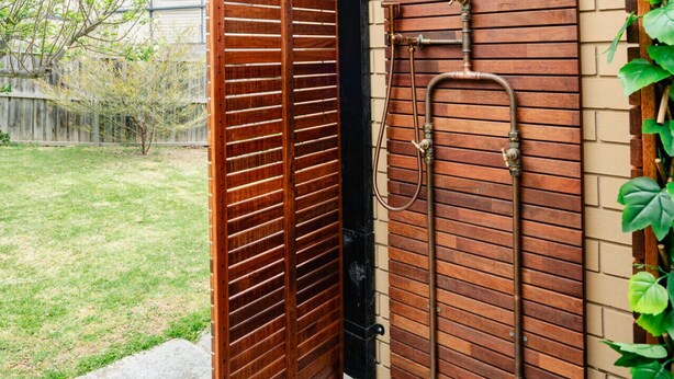 Une porte en bois avec une poignée en métal et un tuyau métallique qui longe le mur.
