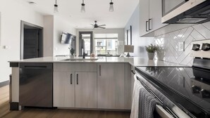 Uma cozinha moderna com ilha central, eletrodomésticos de aço inoxidável e ventoinha no teto.