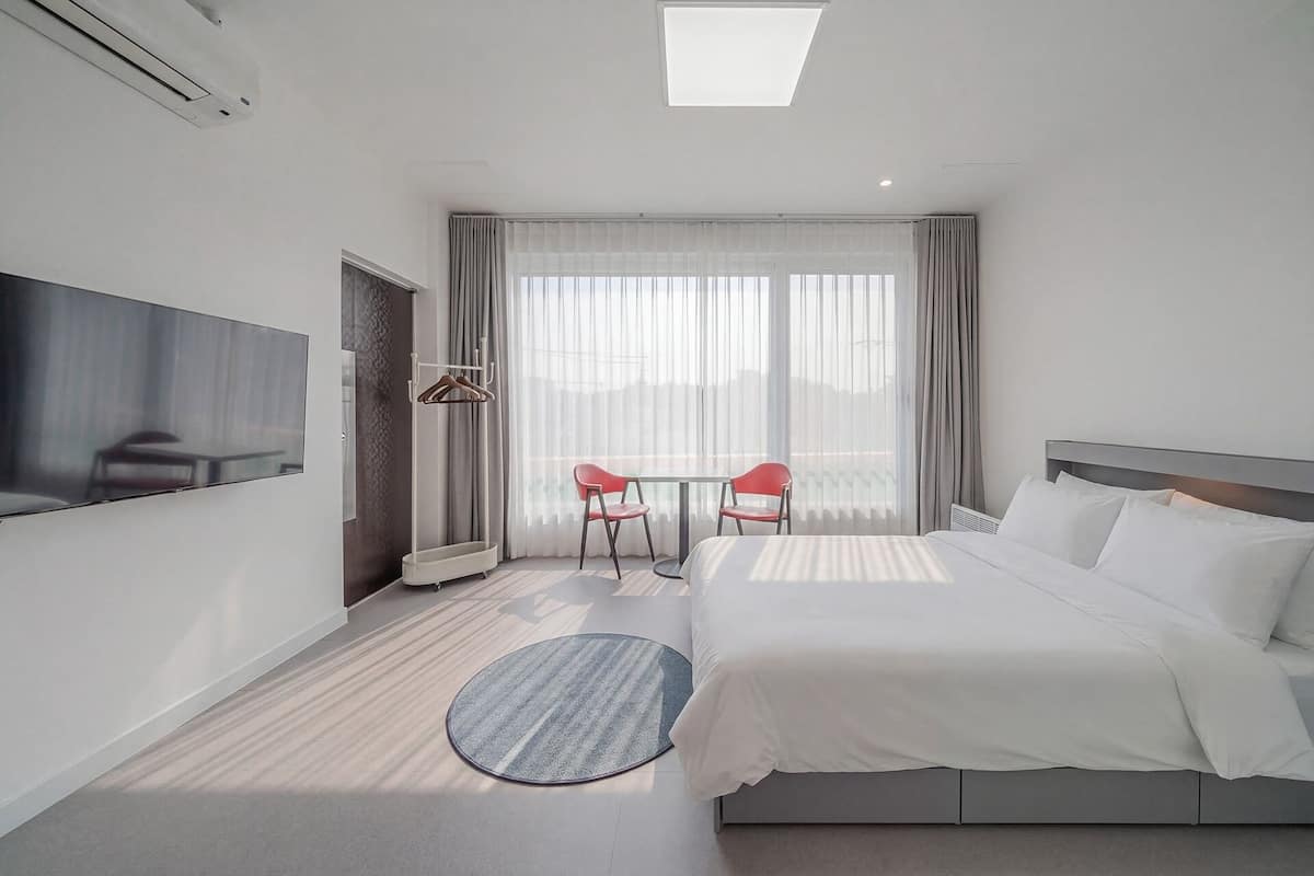 Una habitación de hotel con cama, televisión, escritorio y silla.