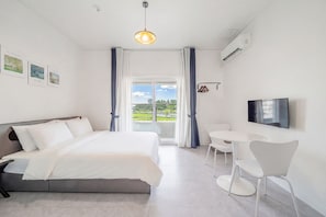 A modern hotel room with a bed, a dining table, chairs, a TV, and a balcony with a view. - Gangneung Gangmun Stay (Gangneung)