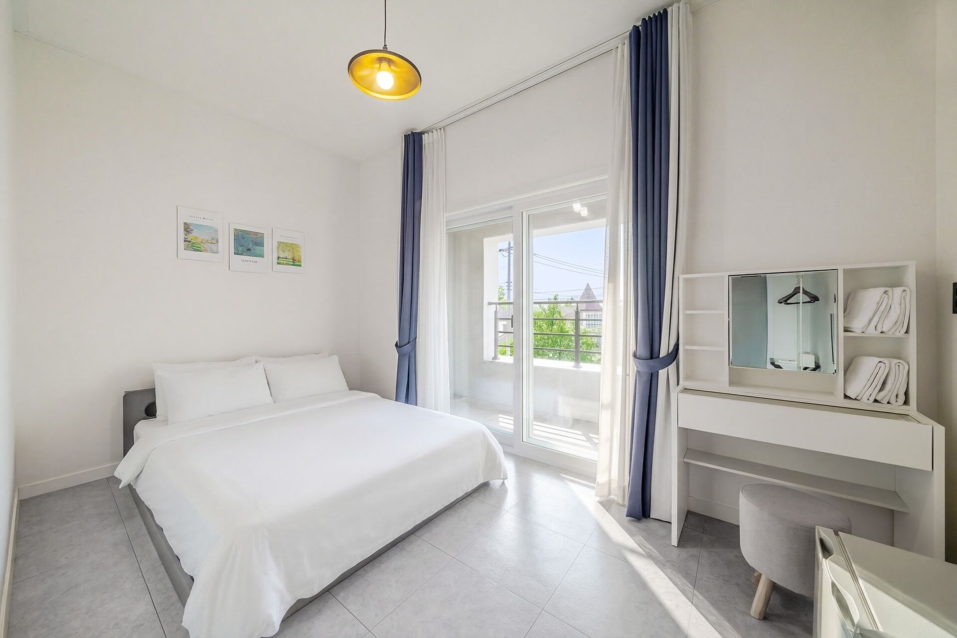 A hotel room with a bed, a desk with a mirror, and a view through a glass door.