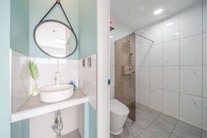 Une salle de bain équipée d’un lavabo, d’un miroir, de toilettes et d’une douche.