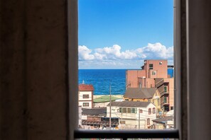 A coastal view through a window, featuring buildings, a clear sky, and the sea. - Gangneung Gangmun Stay (Gangneung)