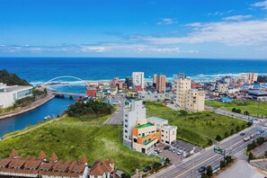 A coastal cityscape with a mix of modern and traditional architecture, a bridge over the water, and a clear view of the sea. - Gangneung Gangmun Stay (Gangneung)