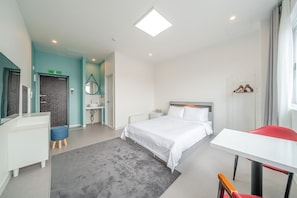 A hotel room with a bed, a desk, a chair, a mirror, a wardrobe, and a bathroom. - Gangneung Gangmun Stay (Gangneung)