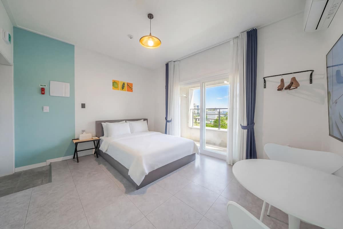 Una habitación de hotel con cama, mesita de noche y vistas al exterior.