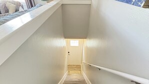 A staircase with a handrail, leading to a door with a small window. - New Reno 1.3M 2 Beach Full Kit, W&D, Large 2BD 2BA (Bonita Springs)