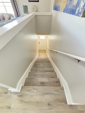 A staircase with a handrail, leading to a door with a small window. - New Reno 1.3M 2 Beach Full Kit, W&D, Large 2BD 2BA (Bonita Springs)