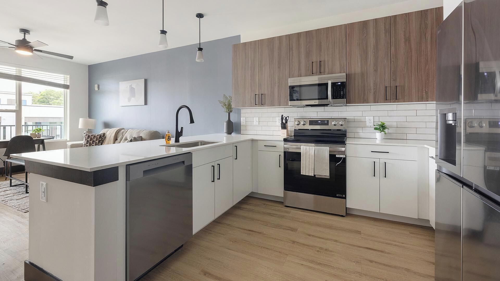 A modern kitchen with a central island, stainless steel appliances, and light wood cabinetry.