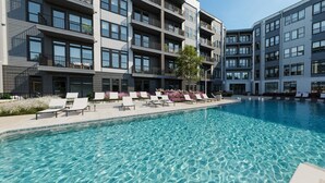 Un bâtiment moderne doté d’une piscine, de chaises longues et d’une eau cristalline.