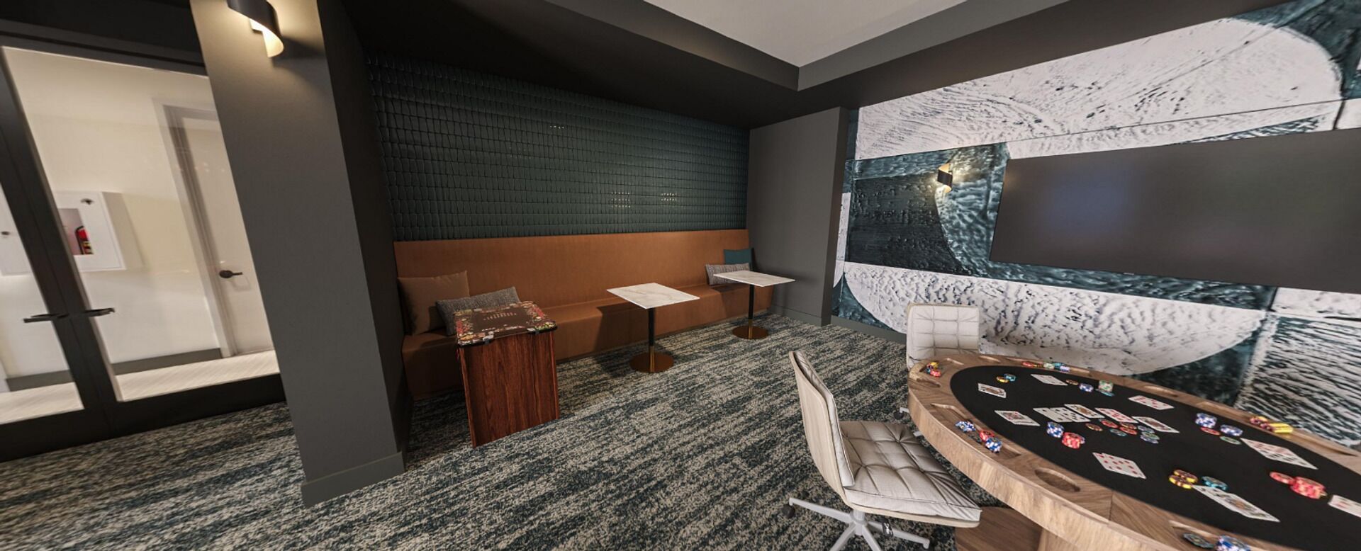 A room with a poker table, a sofa, a small table with a lamp, and a large abstract wall mural.