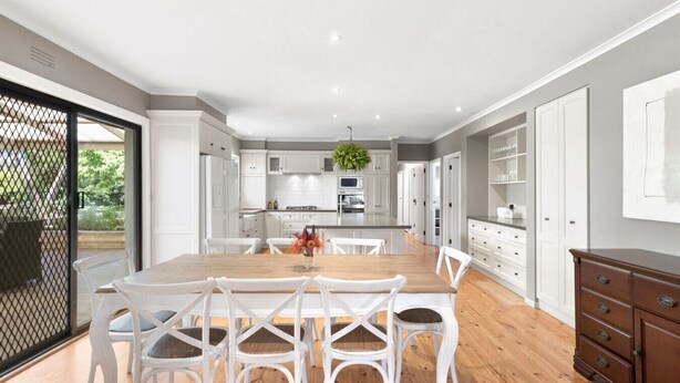 A modern kitchen with white cabinetry, a wooden dining table, and white chairs.