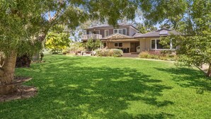 A two-story house with a front porch, a covered patio, and a well-maintained lawn.