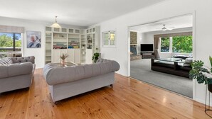 A modern living room with a fireplace, built-in bookshelves, and a large window offering a view of the outdoors.