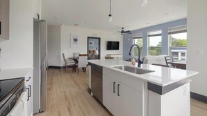 Una cocina moderna con una isla central, electrodomésticos integrados y un comedor con sillas.