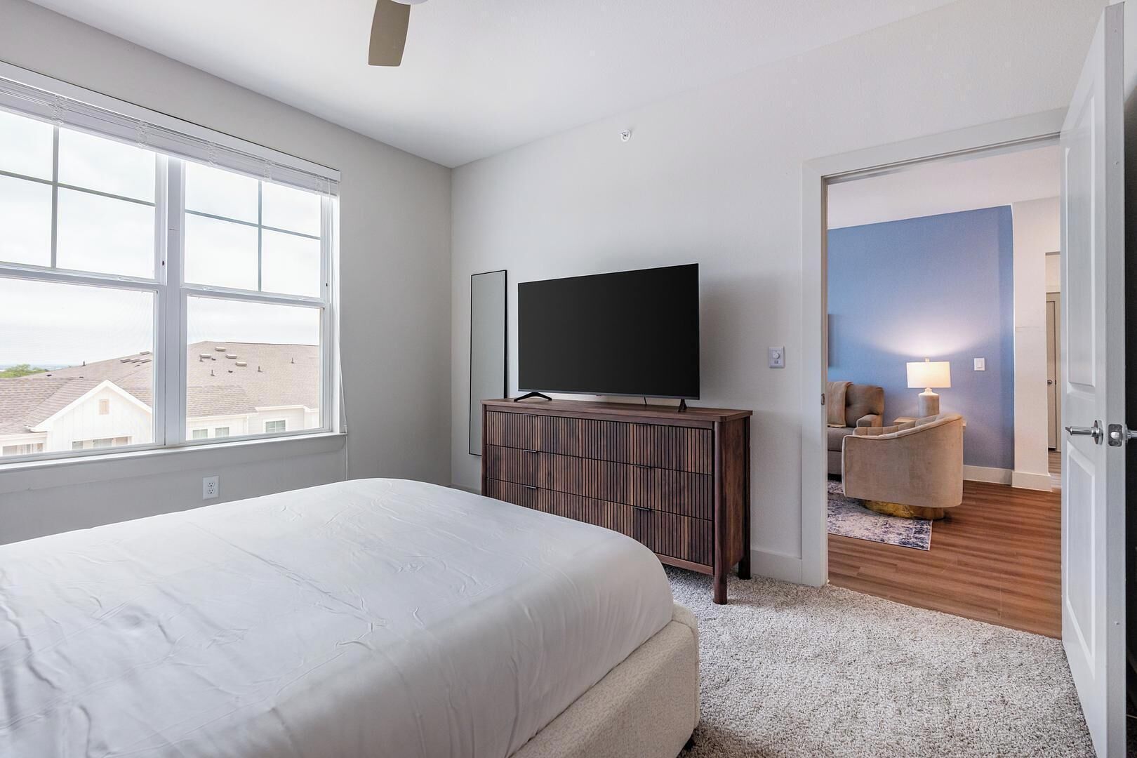 Ein Schlafzimmer mit einem Bett, einem Fernseher auf einer Holzkabine und Blick ins Freie.