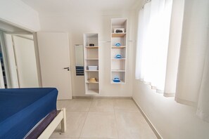 Une chambre à coucher comprenant un lit, une armoire, une étagère et une fenêtre avec des rideaux.