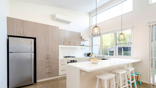 Una cocina moderna con una isla central, electrodomésticos de acero inoxidable y un amplio ventanal que proporciona luz natural.