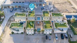 Un hotel con varias piscinas en la azotea, un patio central y una zona de estacionamiento.