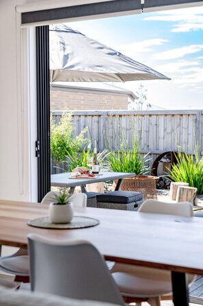 Een terras buiten met een eettafel, een bloempot en een houten hek op de achtergrond.