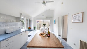 A modern kitchen with a wooden island, white cabinets, and a ceiling fan. - The Grove - Sleeps 6 - Pet Friendly! (499545) (Ocean Grove)