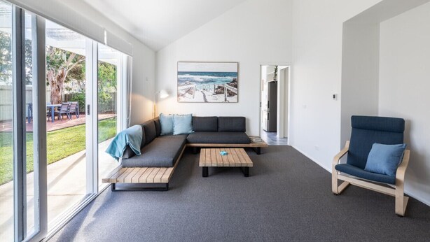 A modern living room with a sectional sofa, a wooden coffee table, and a blue armchair. - The Grove - Sleeps 6 - Pet Friendly! (499545) (Ocean Grove)