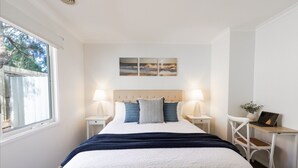 A bedroom with a bed, two bedside tables, a desk, a chair, and a window. - The Grove - Sleeps 6 - Pet Friendly! (499545) (Ocean Grove)