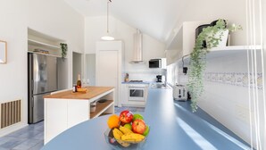 A modern kitchen with a blue countertop, stainless steel appliances, and a fruit bowl. - The Grove - Sleeps 6 - Pet Friendly! (499545) (Ocean Grove)