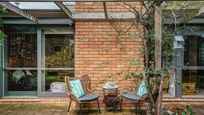 Un patio al aire libre con sillas de mimbre, una mesita y plantas en macetas.